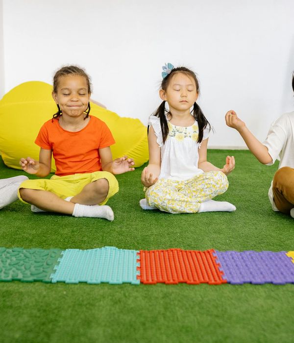 A group of children playfully learning yoga together.